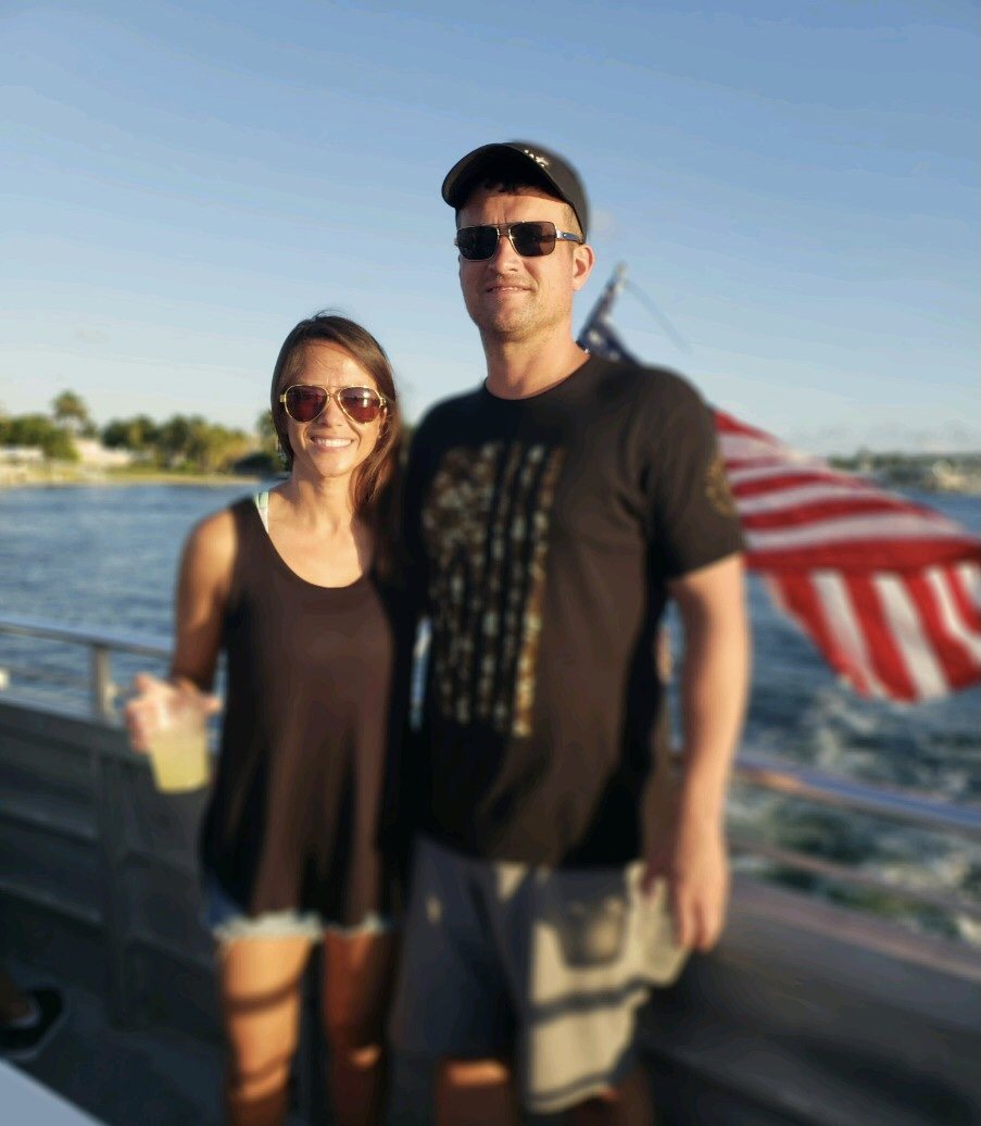 Couple standing beside the water with an American flag behind them